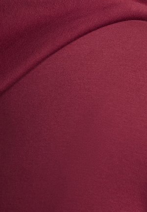 Zbliżenie na złożoną burgundową tkaninę pokazującą gładką i miękką teksturę z drobnym wzorem dzianiny.