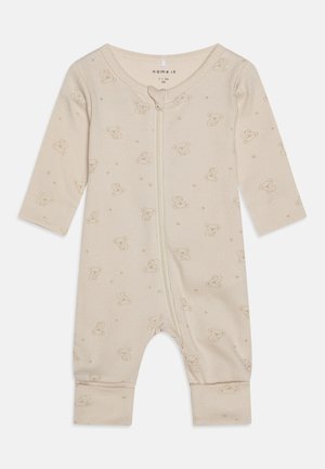 Combinaison pour bébé de couleur crème en tissu côtelé, dotée d'une fermeture éclair à l'avant et d'un imprimé ours en peluche sur l'ensemble, agrémenté de petits points.