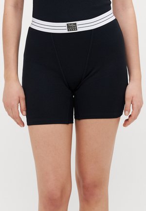 Shorts neri a coste con una cintura elastica a righe bianche e dettaglio del logo. Il design presenta una vestibilità aderente e una texture liscia.