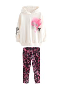 White hoodie with pink heart graphic, black accents, and balloon sleeves. Black leggings with pink abstract pattern. Smooth fabric texture.