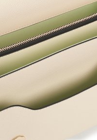 Borsa in pelle beige con superficie texturizzata, dotata di un interno verde e una cerniera nera. Inclusa una finitura in colore oro.