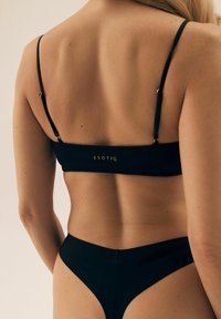 Czarny zestaw bikini z cienkimi regulowanymi ramiączkami, bezszwowym paskiem z złotym logo "ESOTIQ" oraz wysokim stanem dolnych części z wycięciami.