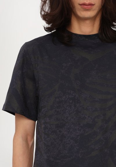 Tricou cu mânecă scurtă dintr-o țesătură în navy închis, cu o textură subtilă și un model abstract vag. Prezintă un guler înalt și o croială lejeră.