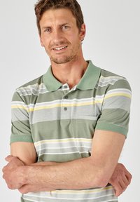 Gestreept polo-shirt in groen, grijs en gele tinten. Korte mouwen, een klassieke kraag en een detail met een voorzakje. Zachte, gestructureerde stof.