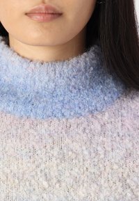 Maglione in maglia con colletto alto e testurizzato. Caratterizzato da una sfumatura di colori pastello con una consistenza morbida e soffice. Dettaglio ravvicinato del collo.