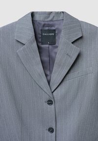 Blazer grigio a righe con revers a soffietto, due bottoni neri e taschino sul petto, etichettato come taglia small da Calliope.