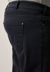 Vaqueros de mezclilla azul marino oscuro con un corte ajustado, que cuentan con bolsillos traseros y detalles de costura sutiles. Textura suave y un diseño clásico.