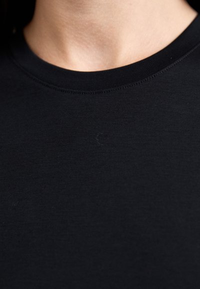 Black cotton t-shirt featuring a crew neckline and short sleeves. The fabric is smooth with minimal texture and slight lint visibility.