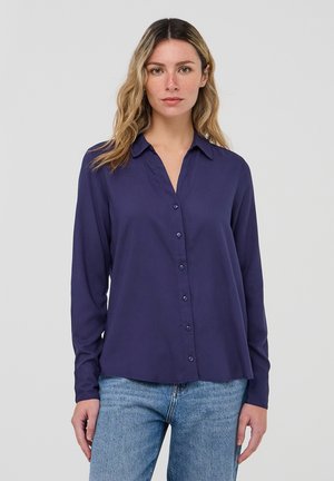 Camicia a maniche lunghe blu navy realizzata in tessuto morbido. Presenta un'apertura con bottoni e un colletto a punte. Orlo dritto e vestibilità rilassata.