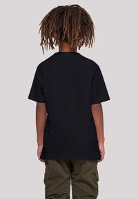 Camiseta de algodón negra con mangas cortas, con un escote redondo y una textura suave, combinada con pantalones cargo verde oliva.