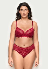 Punainen pitsinen rintaliivi säädettävillä olkaimilla, jossa on aaltoileva reuna ja vaijeri. Yhdiste muuassa korkea vyötäröinen pitsialushousut, molemmissa kukkakuosi.