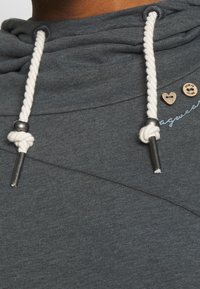Grijze hoodie met een zachte textuur, voorzien van een witte trekkoord, zilverkleurige details en kleine houten hart- en knoopaccenten.