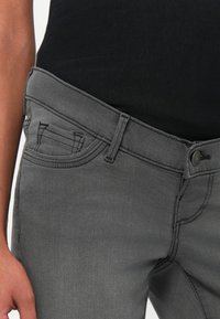 Gray denim jeans with a slim fit, featuring a classic waistband, front pocket, and contrasting stitching details.