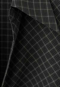 Tissu à carreaux noir et gris plié, montrant des lignes blanches fines et entrecroisées formant des motifs carrés sur un matériau doux.