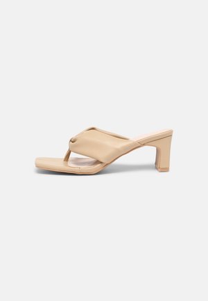 Beige åben tå med hæl sandal med polstret tårem og blokhæl, vist i sideprofil på ensfarvet lyst baggrund.