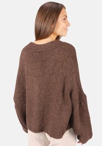 Brauner Strickpullover mit lockerem Schnitt, weiten Ärmeln, gerippter Textur und rundem Ausschnitt. Die Rückseite hat eine subtile Nahtdetails.