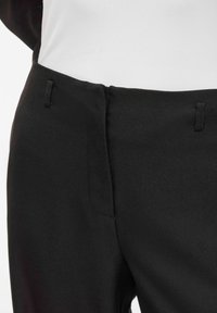 Črne hlače po meri z gladkim teksturo, srednje visokim pasom in diskretnimi stranskimi žepi z nežnimi šivi.