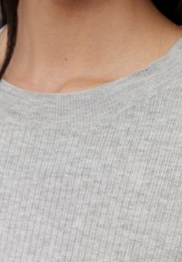 Suéter de punto acanalado gris con cuello redondo y textura suave, que presenta sutiles variaciones de tono y una silueta ajustada.