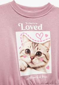 Sudadera rosa con un gráfico de un gato de grandes ojos, acentos en forma de corazón, y texto que dice "Es hora de ser amado" y "No puedo tener suficiente de los besos."