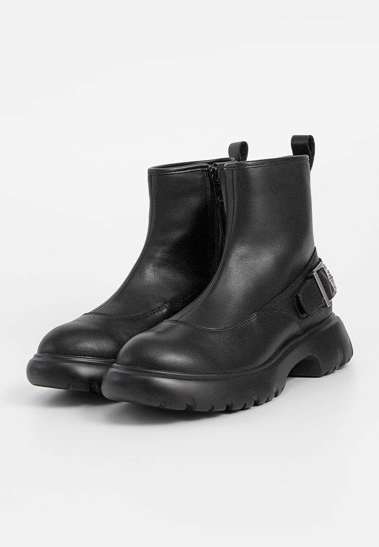 Schwarze Lederstiefeletten mit einem seitlichen Reißverschluss, runder Zehenform, klobiger Sohle und einem Riemen-Detail mit metallischen Beschlägen.