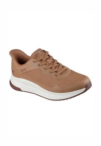 Zapato deportivo marrón con parte superior de malla y suela de goma. Presenta cierre con cordones, cuello acolchado y acentos texturizados en los laterales.