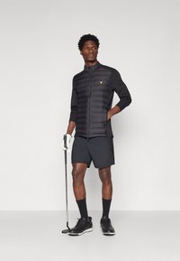 Svart vadderad jacka med långa ärmar, tillsammans med svarta shorts. Tillbehör inkluderar en golfklubba och vita handskar. Svarta skor och strumpor fulländar looken.