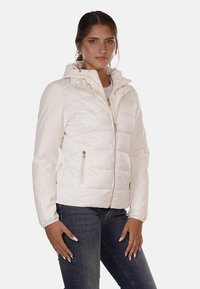 Giacca bianca imbottita con cappuccio e zip frontale. Presenta tasche laterali e polsini elastici. Texture liscia con un leggero luccichio.