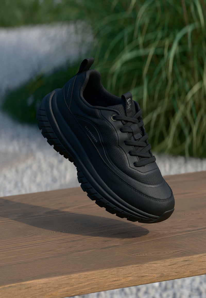 Μαύρα αθλητικά παπούτσια με υφασμάτινη υφή, παχιά ελαστική σόλα και έντονες αυλακώσεις. Διαθέτουν κορδόνια και λαβή για εύκολη εφαρμογή.