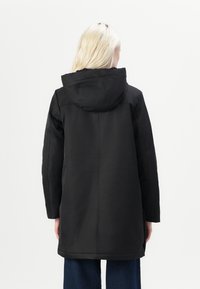 Black hooded coat with a straight cut, minimal seams, and a textured fabric. Features a mid-length design for added coverage.
