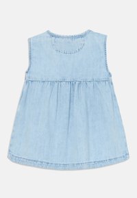 Top sin mangas de denim azul claro con escote redondo, cintura fruncida y parte inferior acampanada. Textura suave con un acabado uniforme.