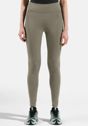 Hochgeschnittene, eng anliegende Leggings aus leicht olivgrünem Stoff, mit einer glatten Textur und einem Logo am Bund.