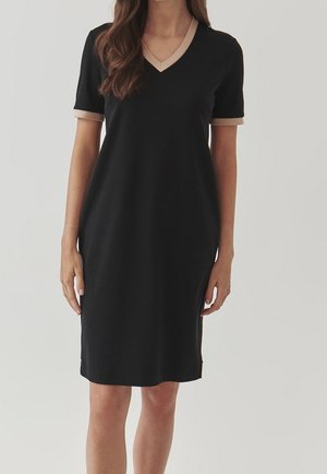 Robe noire avec un décolleté en V et des manches courtes, présentant une bordure beige contrastante au niveau du col et des manches. Tissu lisse, coupe à mi-genoux.