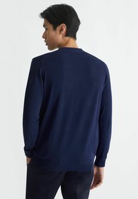 Maglione navy a maniche lunghe realizzato in tessuto morbido. Presenta un collo rotondo, polsini a coste e un orlo dritto, con un design semplice.