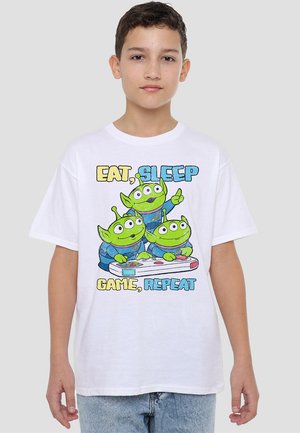 White cotton t-shirt featuring a graphic of three green aliens playing video games. Text reads "EAT, SLEEP, GAME, REPEAT" in colorful font.