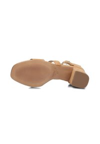 Beige suède sandalen met hak, voorzien van een verstelbare enkelriem, een vierkante neus en een rubberen zool met textuur en horizontale groeven voor grip.