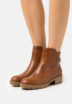 Braune Leder-Stiefeletten mit niedrigem Absatz, runder Spitze, einer seitlichen Schnallenakzentuierung und einer strukturierten Gummisohle für bessere Griffigkeit.