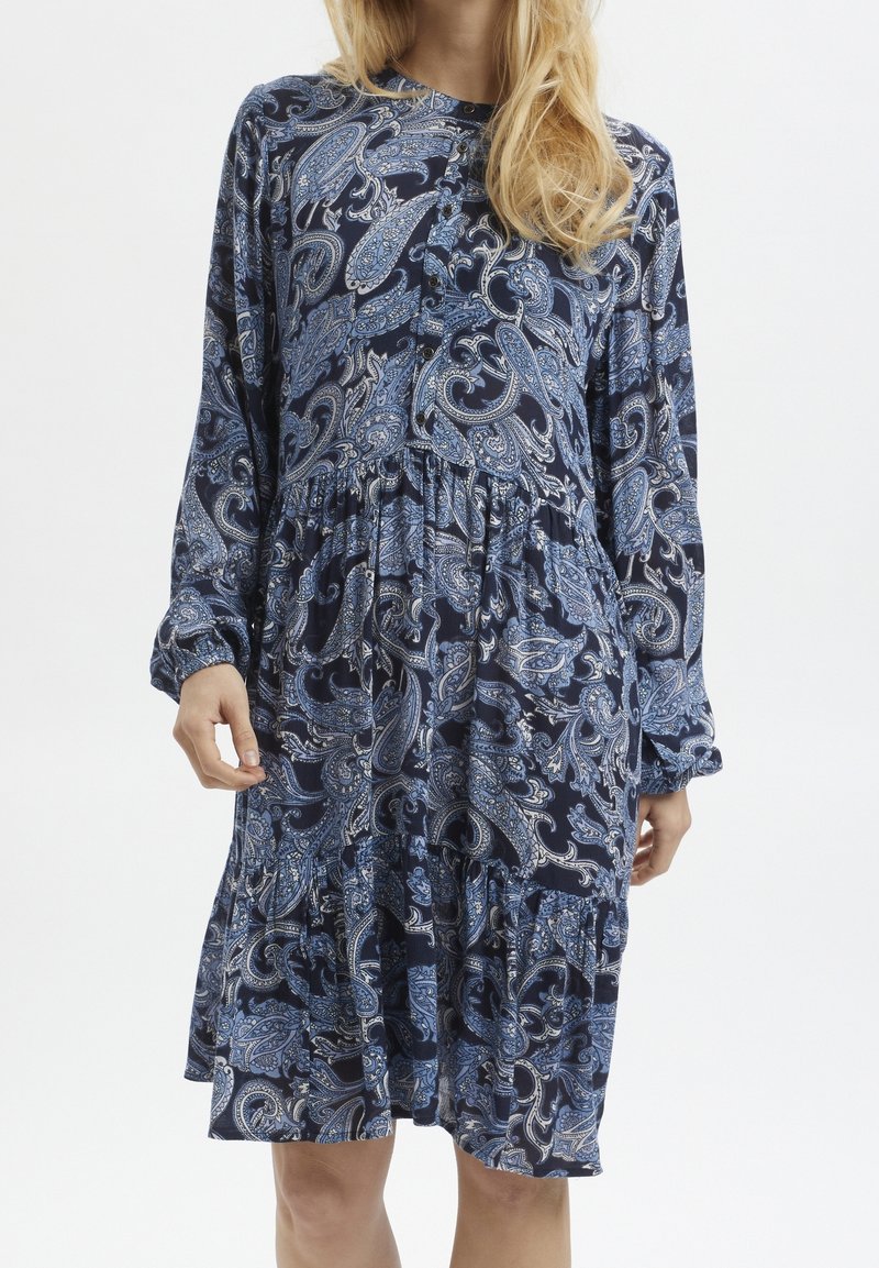 Robe bleu marine à motif paisley avec manches longues, fermeture boutonnée sur le devant, et taille cintrée. Comprend un ourlet à volants et une texture de tissu douce.