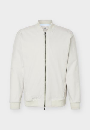 Balta zipa aizdare bomber jaka ar ribveida aprocēm un apakšmalu, stāvošu apkakli un smalku Adidas logotipu apkakles iekšpusē.