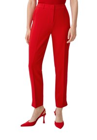 Pantalons tailleur rouges avec une texture lisse, présentant une coupe droite et un pli avant. Associés à des talons slingback rouges.