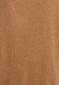 Tecido de malha bege quente com uma textura suave e um brilho subtil, apresentando uma trama fina e consistente por todo o comprimento.