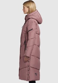Lange roze pufferjas met een capuchon, voorzien van horizontale gestikte panelen, zwart ritszakken en een logo patch nabij de zoom.