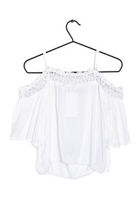 White off-the-shoulder blouse with lace trim at the neckline, lightweight fabric, flowing sleeves, and a rounded hem. Hangs on a black hanger.