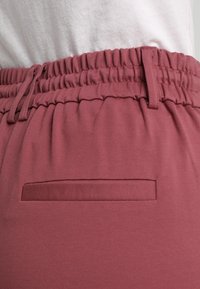 Burgundské kalhoty s elastickým pasem a nabíranou strukturou, se plochou zadní kapsou a hladkým povrchem.