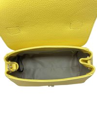 Żółta skórzana torebka o teksturowanej powierzchni, otwarta u góry, odsłaniająca szary środek oraz okrąły detal ze stali na jednym boku.