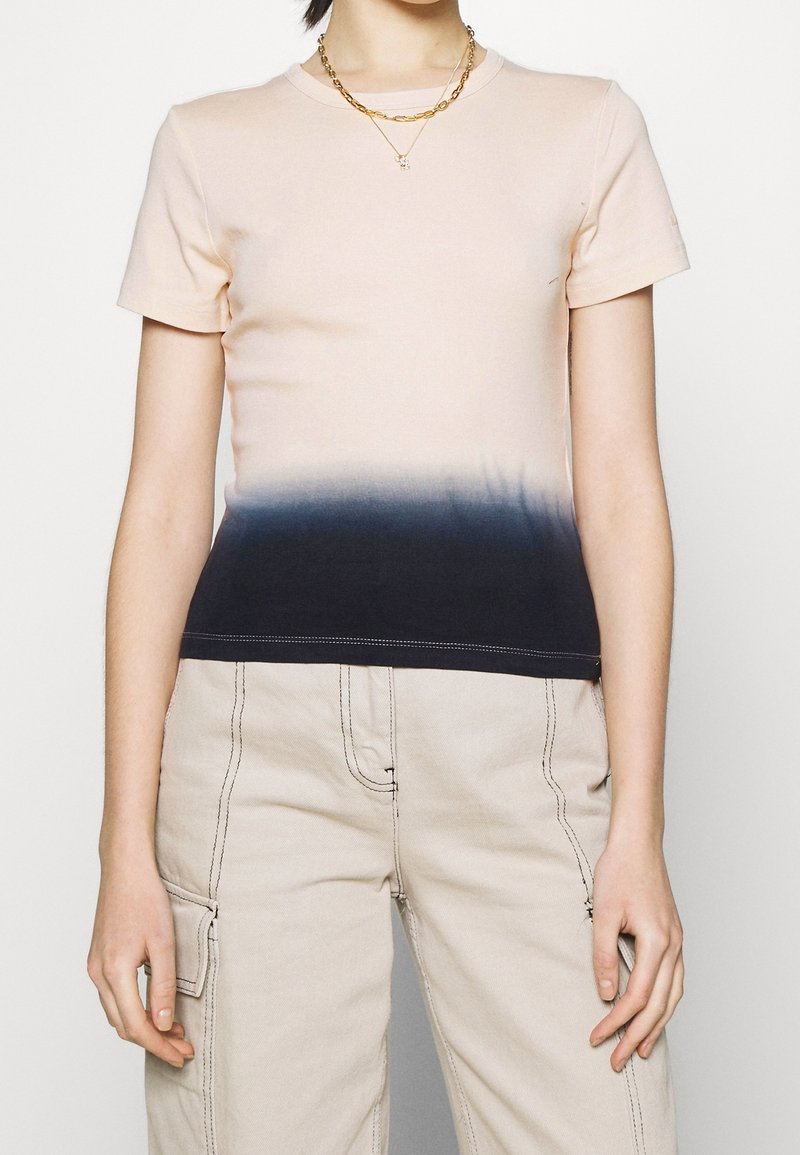 T-shirt à manches courtes en coton rose clair, dégradé vers un bleu marine foncé à l'ourlet, avec des coutures contrastées et un col rond.