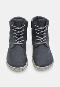 Črne gležnarje z teksturiranim zgornjim delom, kontrastnimi vezalkami in pikčasto podplatom. Oblikovanje vključuje zaobljen nos in oblazinjen ovratnik.