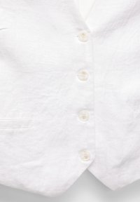 Gilet en lin blanc avec cinq boutons blancs, deux poches latérales et un design à revers cranté. Présente une surface de tissu légèrement texturée.