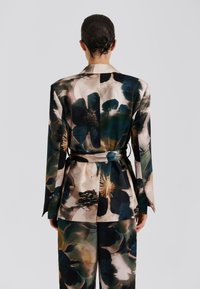 Σατέν σακάκι με φλοράλ μοτίβο, μακριά μανίκια, ζώνη στη μέση και αφηρημένο σχέδιο σε αποχρώσεις σκούρου πράσινου, μπεζ και απαλού ροζ.