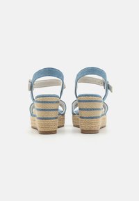 Sandales compensées en denim bleu avec une plateforme en jute tressé, dotées de rayures blanches et de brides à la cheville pour un maintien sûr.