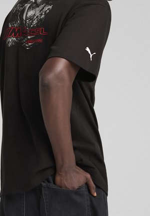 Černé bavlněné tričko s grafickým designem a červenými akcenty, s logem Puma na rukávu. Krátké rukávy, uvolněný střih.